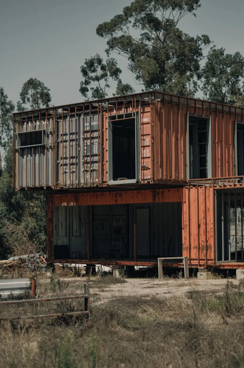 Halimbawa ng larawan ng BookNoFees: Dalawang-palapag na container house na may malalaking bintana na nakapuwesto sa gitna ng mga puno