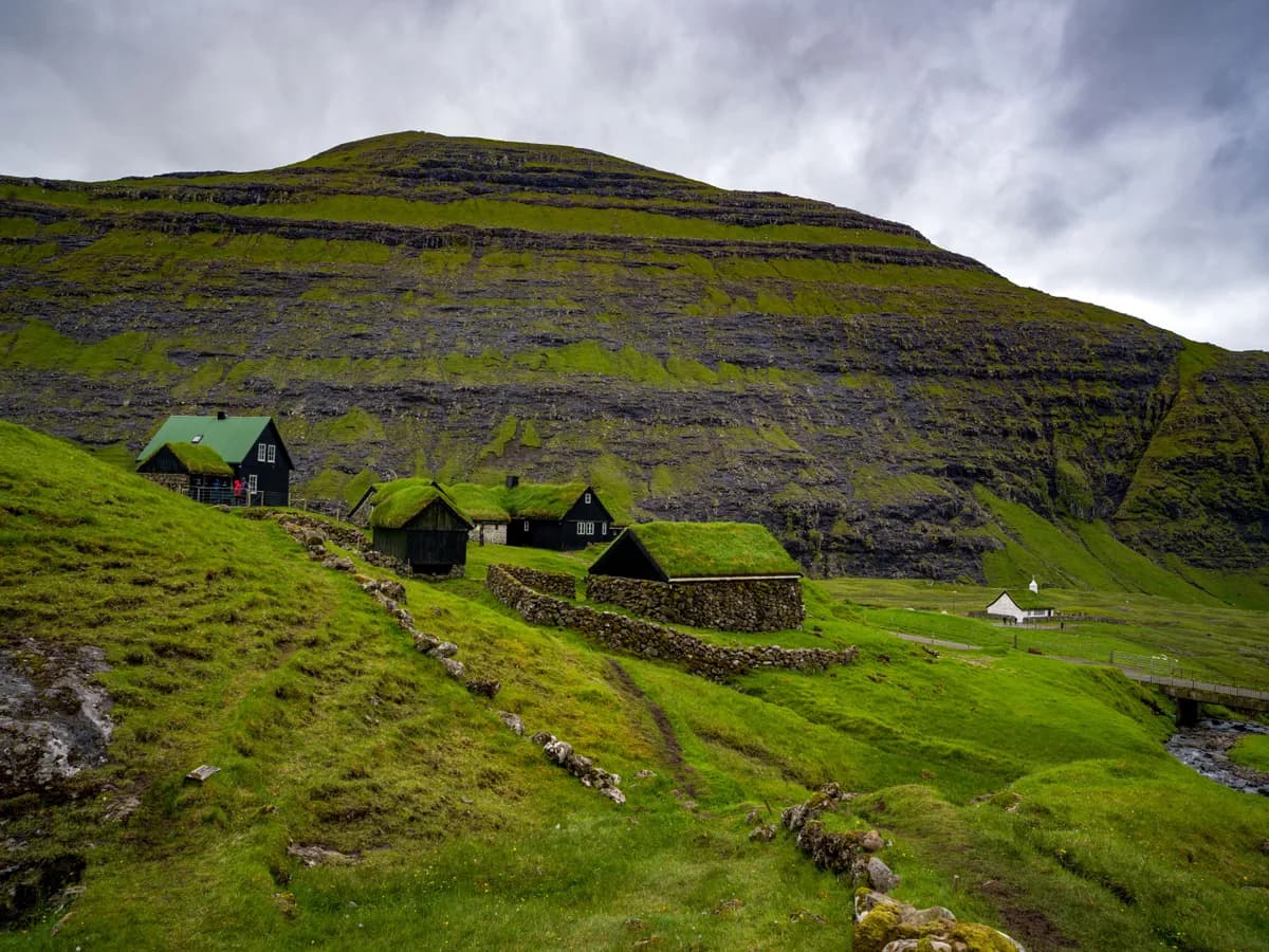BookNoFees example image: Houses with grass-covered roofs in a landscape on the Faroe Islands
