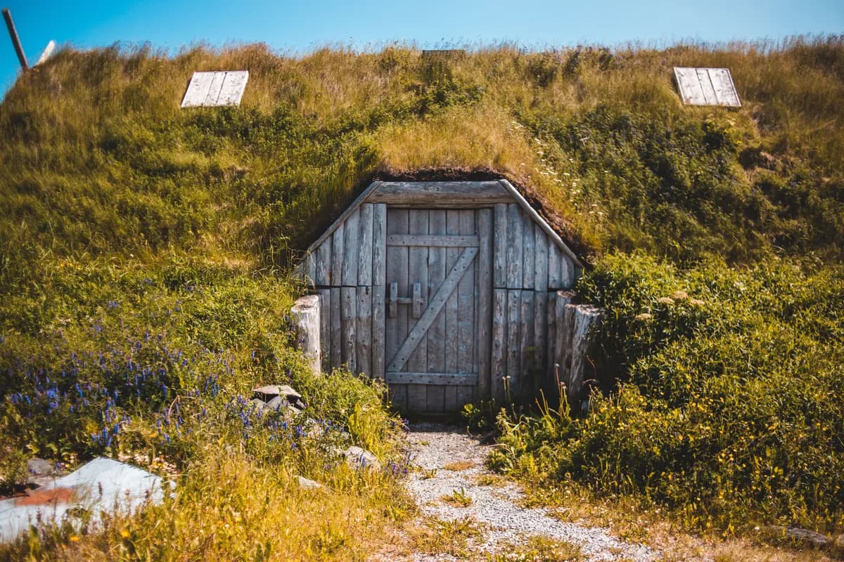 BookNoFees example image: A structure covered with earth and grass, featuring low wooden doors