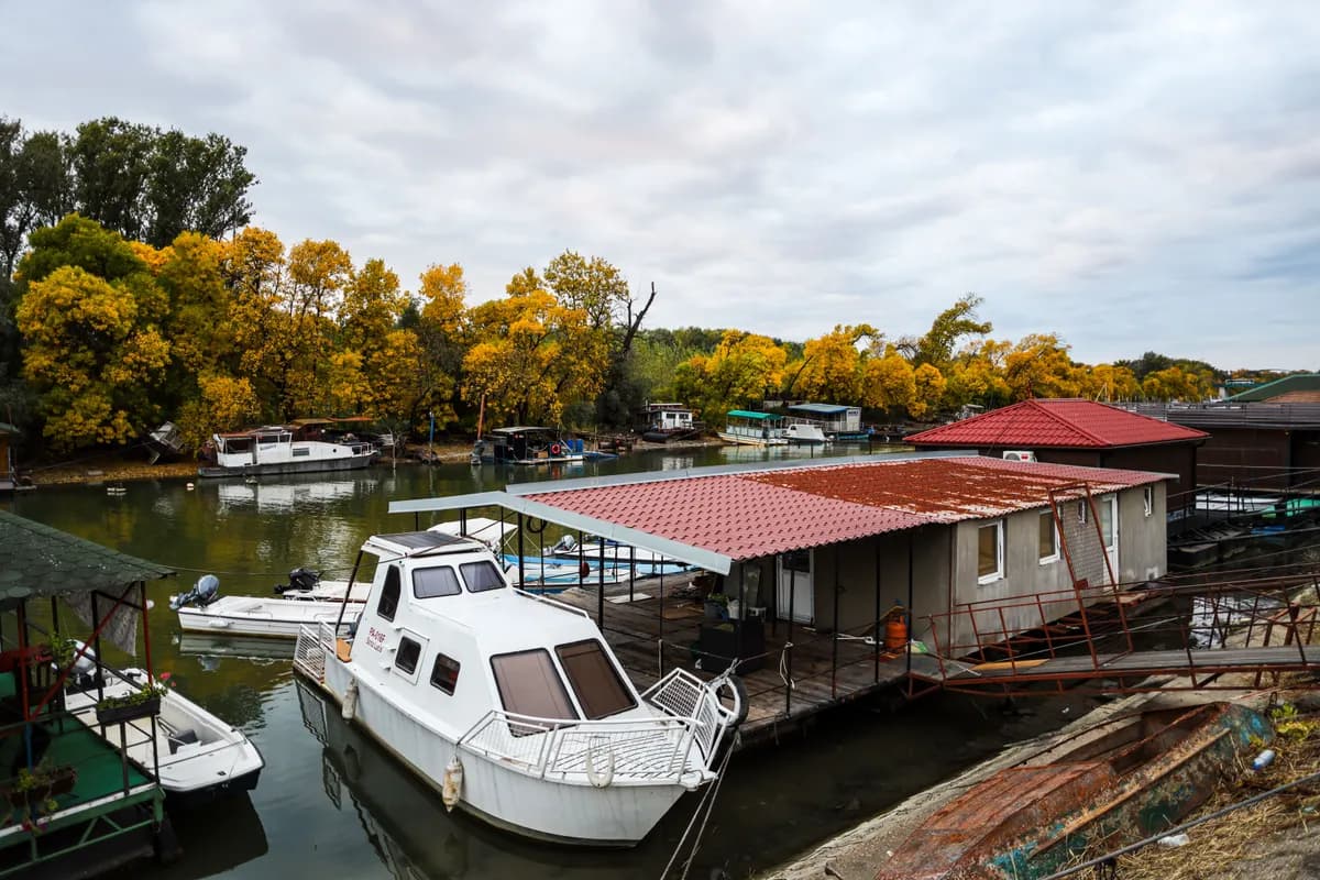 BookNoFees sample image: Houseboat at a dock with autumnal trees on the shore