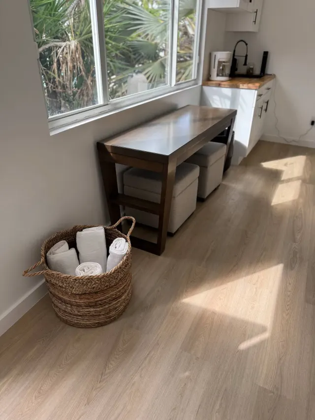 BookNoFees vacation rental in Cutler Bay, United States – Kitchen corner with wooden table, woven basket of towels, and window overlooking palms