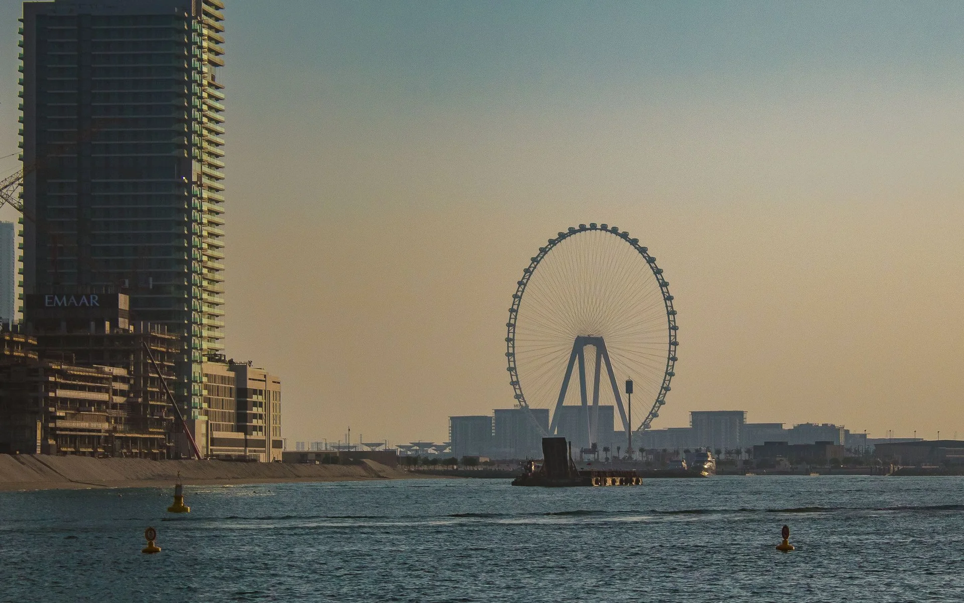 Tanawin ng Dubai skyline na may Ferris wheel sa paglubog ng araw