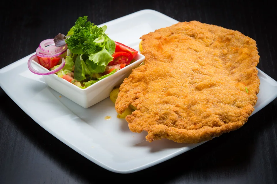 BookNoFees: Halimbawa ng larawan: Schnitzel na pinahiran ng breading na may salad sa gilid sa puting plato