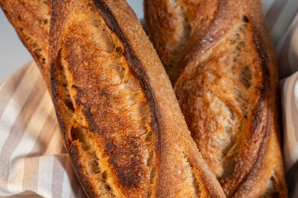 BookNoFees: Halimbawa ng larawan: Mga baguette na gintong-kayumanggi na nakapatong sa telang kuwadro-kuwadro