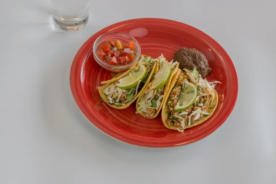 BookNoFees: Halimbawa ng larawan: Tatlong taco na may hiwang pakwan sa ibabaw, na may salsa sa pulang plato